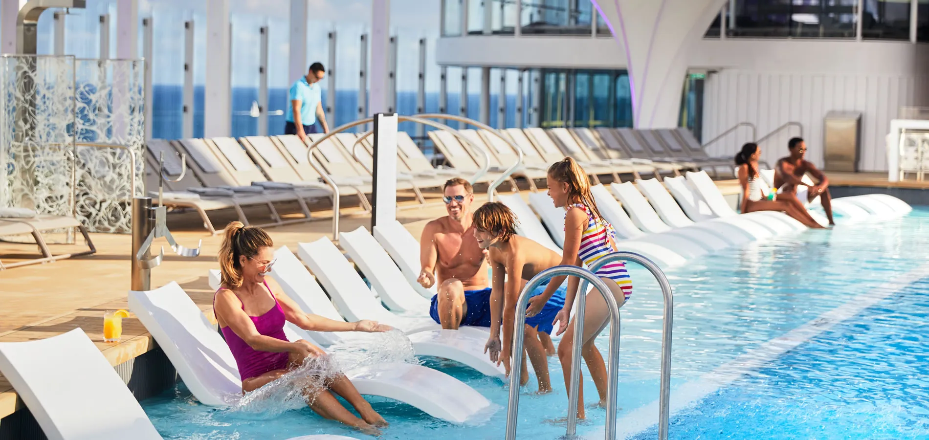 Family enjoying pool area with lounge chairs on a sunny cruise ship deck