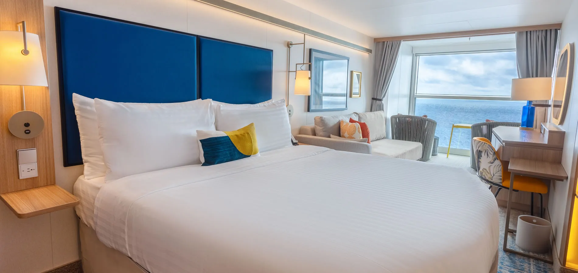 Modern hotel room with ocean view and blue headboard