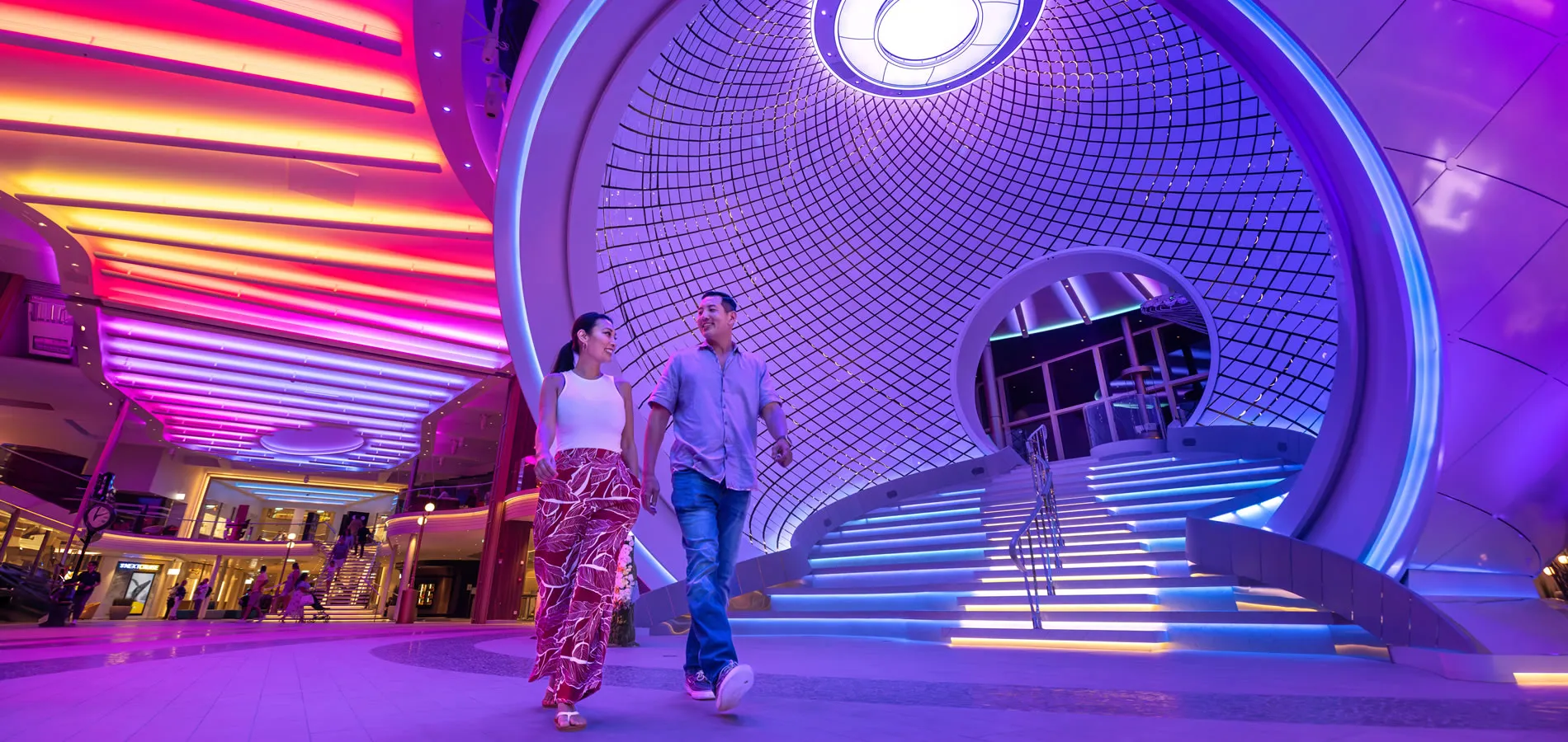 Futuristic mall interior with colorful lighting and two people walking