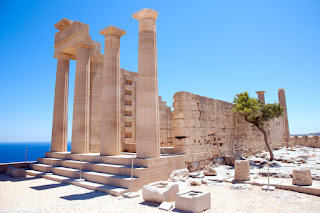 Ancient Greek temple ruins overlooking blue sea with stone columns