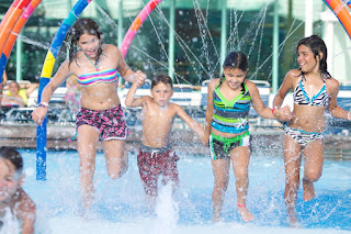 Children playing and splashing in colorful water park fountain
