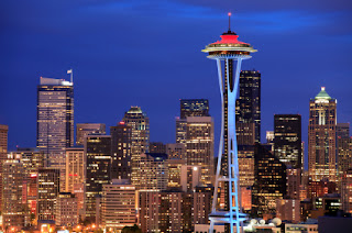 Seattle skyline at night with iconic Space Needle illuminated against blue sky