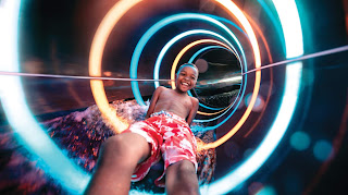 Child lying in colorful illuminated tunnel with glowing circular light rings