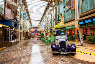 Vintage car displayed in elegant indoor shopping arcade with glass roof