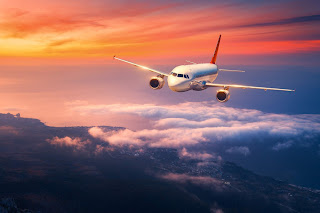 Passenger airplane flying above colorful sunset clouds with dramatic sky
