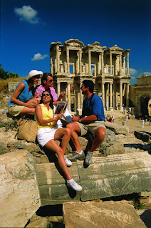 Tourists sitting near ancient Celsus Library ruins in Ephesus, Turkey