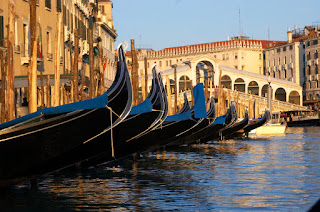 Gondolas moored along Venice canal with Rialto Bridge in background