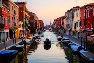 Colorful Venetian canal with boats, historic buildings at sunset