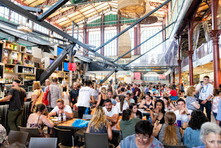 Bustling indoor market with crowds of people dining and shopping
