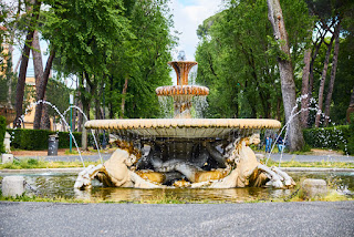 Ornate stone fountain with lion sculptures in a lush green park