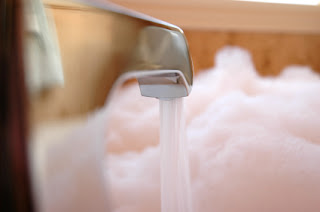 Bathroom faucet running with water streaming into blurry white foam