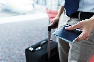 Person holding passport and rolling suitcase at airport or travel destination
