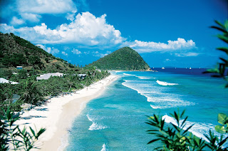 Tropical beach with white sand, turquoise water, and lush green mountains