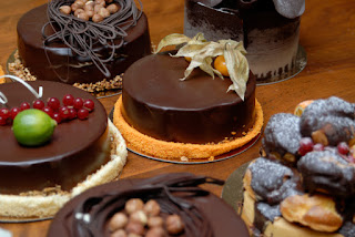 Assorted elegant chocolate desserts with decorative toppings on wooden surface