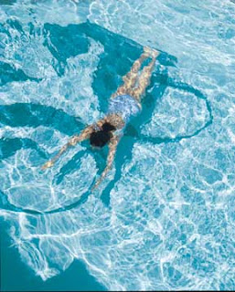 Swimmer floating gracefully in clear, sparkling blue swimming pool water