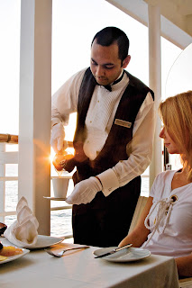 Waiter serves customer at elegantly set table with warm lighting