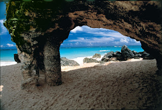 Natural stone arch framing turquoise ocean and sandy beach landscape