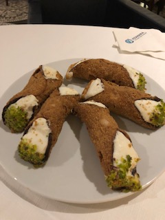 Cannoli with ricotta filling and pistachio ends on white plate