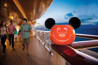 Mickey Mouse balloon on cruise ship deck with people walking at sunset
