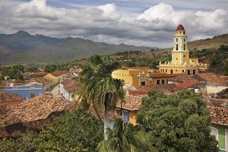 Colonial town with bell tower overlooking lush mountains in Trinidad, Cuba