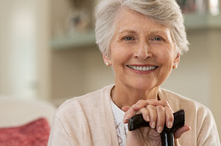 Smiling senior woman leaning on walking cane, looking content and happy
