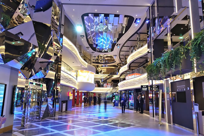 Modern shopping mall with futuristic design, reflective surfaces, and blue lighting