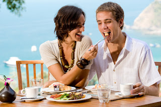 Couple laughing and enjoying breakfast together at seaside cafe