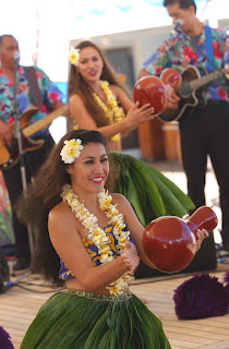 Hawaiian performers in traditional costumes playing musical instruments and dancing
