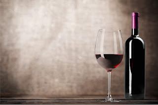 Elegant red wine glass and dark bottle on rustic wooden surface
