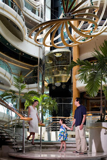 Elegant indoor atrium with large curved chandelier and tropical plants