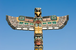 Colorful traditional Native American totem pole against bright blue sky