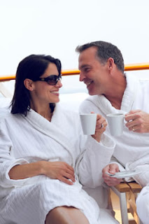 Couple in white bathrobes enjoying coffee together on a sunny deck