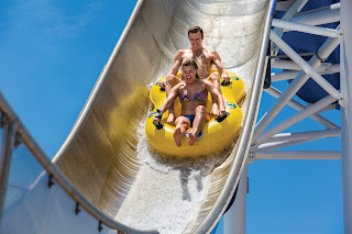 Family sliding down a steep water slide in a yellow inflatable tube