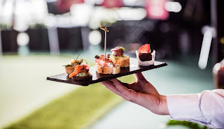 Elegant hand holding gourmet sushi canapes on black serving slate