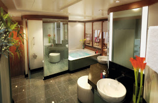 Modern bathroom with glass shower, white fixtures, and decorative red flowers