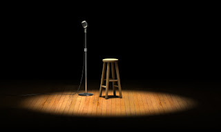 Microphone and stool under spotlight on dark wooden stage