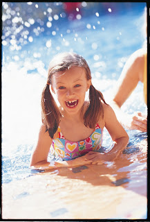 Joyful child splashing and playing in sparkling blue water