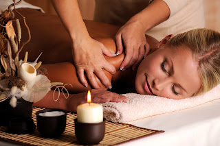 Woman receiving relaxing massage with candles and spa accessories