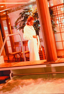 Woman in white dress standing on stage with red-orange lighting