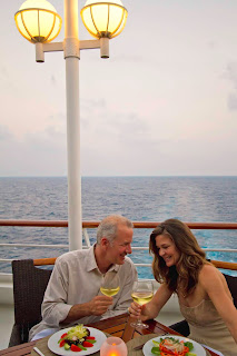 Couple enjoying wine and dinner on cruise ship deck at sunset