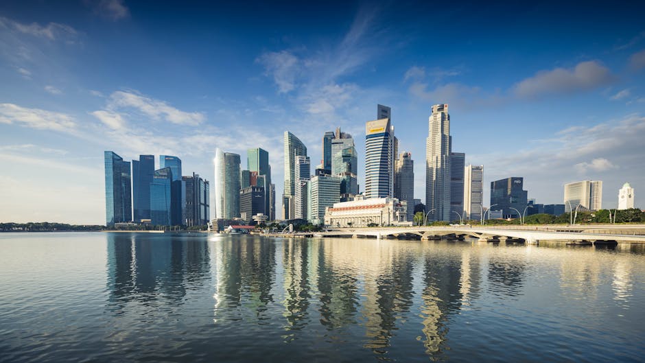Capture of Singapore's modern skyline featuring reflective skyscrapers against a blue sky.