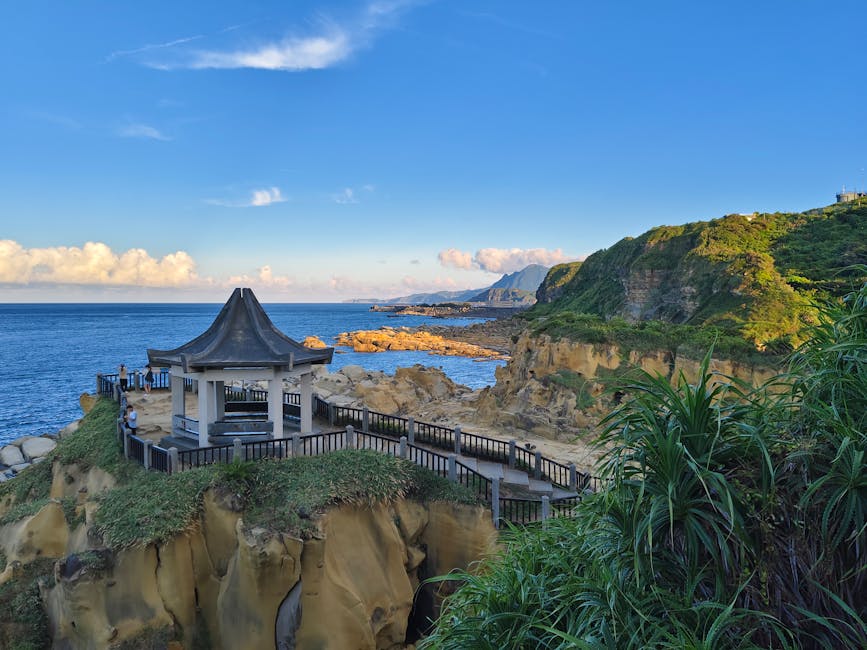 Beautiful view of Bitoujiao Cape's coastal pavilion surrounded by cliffs and ocean under a sunny sky.
