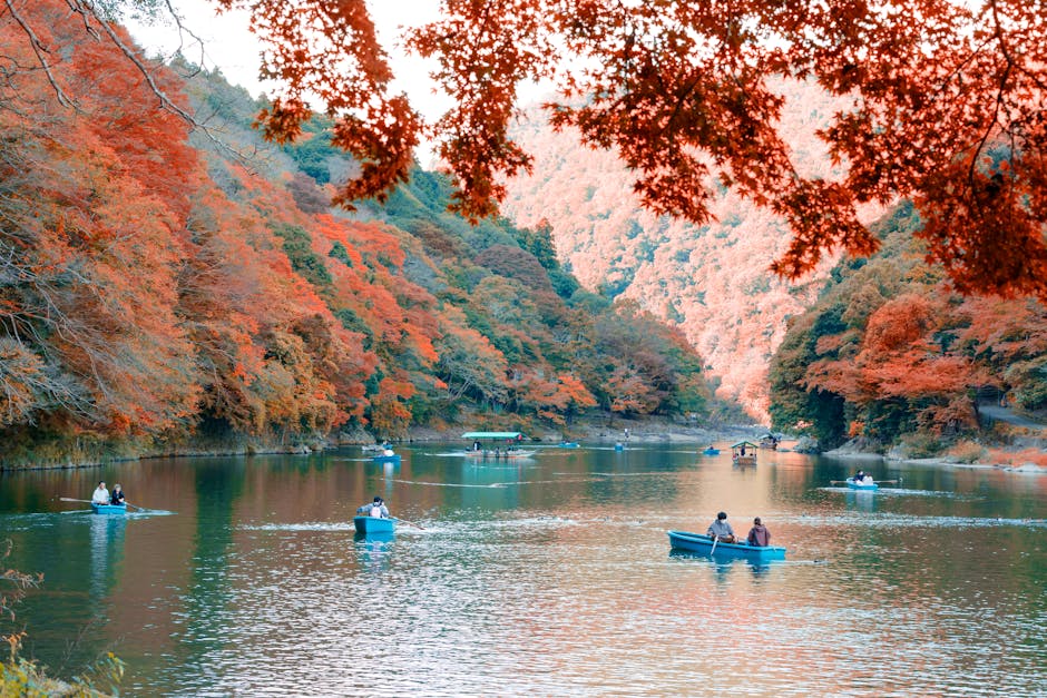 Scenic view of a river with boats under colorful autumn foliage, perfect for outdoor travel themes.
