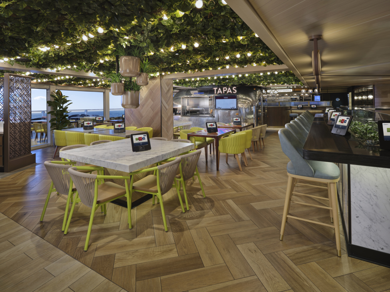 The Tapas Food Truck station and casual seating area within the Indulge Food Hall aboard Norwegian Viva, showcasing the venue's lively market-hall atmosphere.