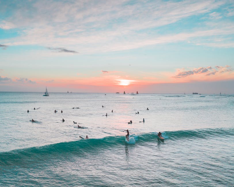 A picturesque scene of surfers riding waves at sunset on a tropical beach, with a vibrant sky creating a serene atmosphere.