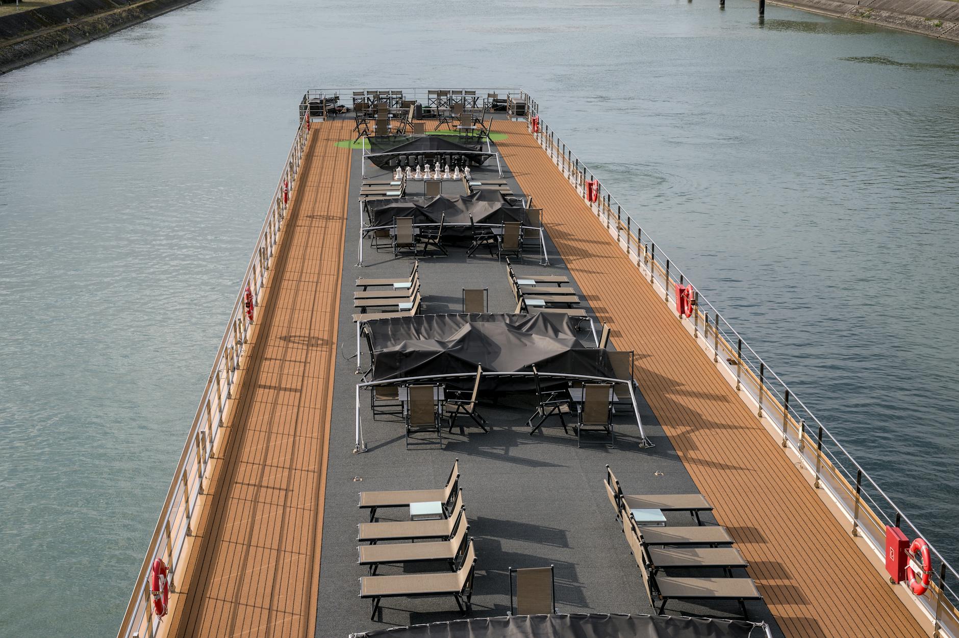 A river cruise ship sundeck with deck chairs set up along the waterway, evoking the intimate, relaxed onboard experience suited to travelers who prefer small-ship cruising through riverside towns.