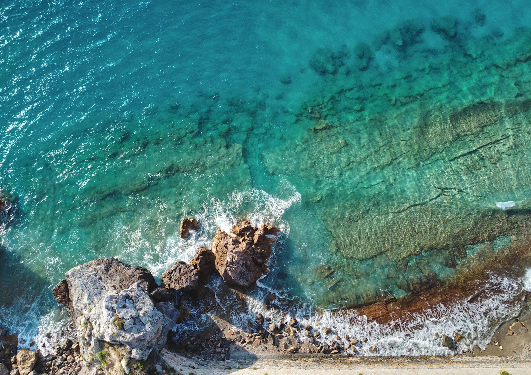 Aerial view of the colorful coastal village of Varigotti along the Ligurian coastline, with rugged cliffs meeting turquoise Mediterranean waters — a quintessential stop on a Mediterranean cruise route.