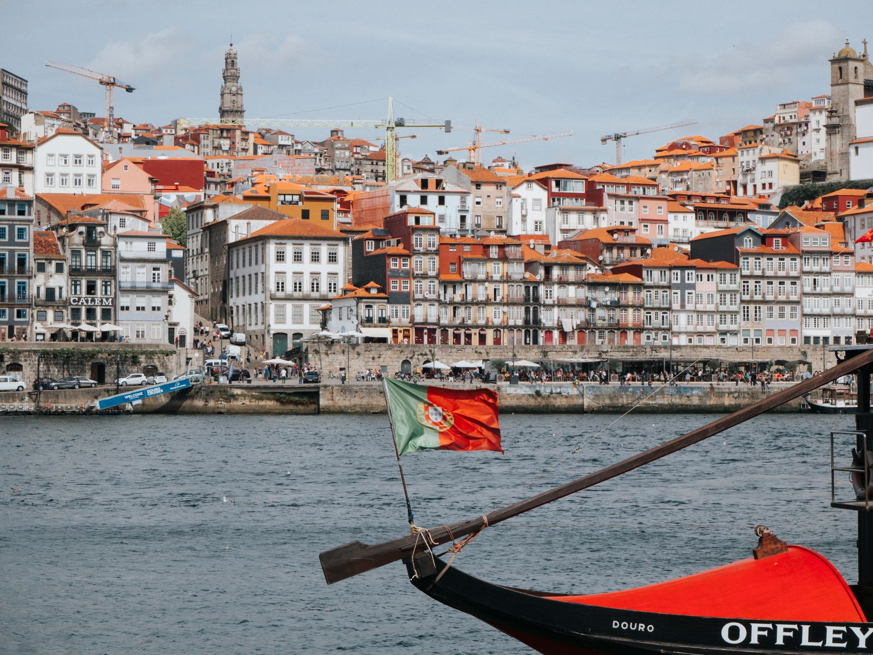 Colorful Ribeira District in Porto with Douro River and traditional Rabelo boat.