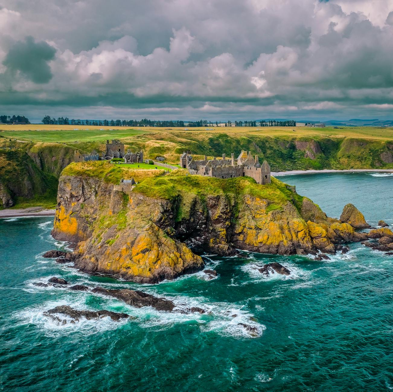 Stunning aerial view of Dunnottar Castle perched on cliffs along the Scottish coastline.