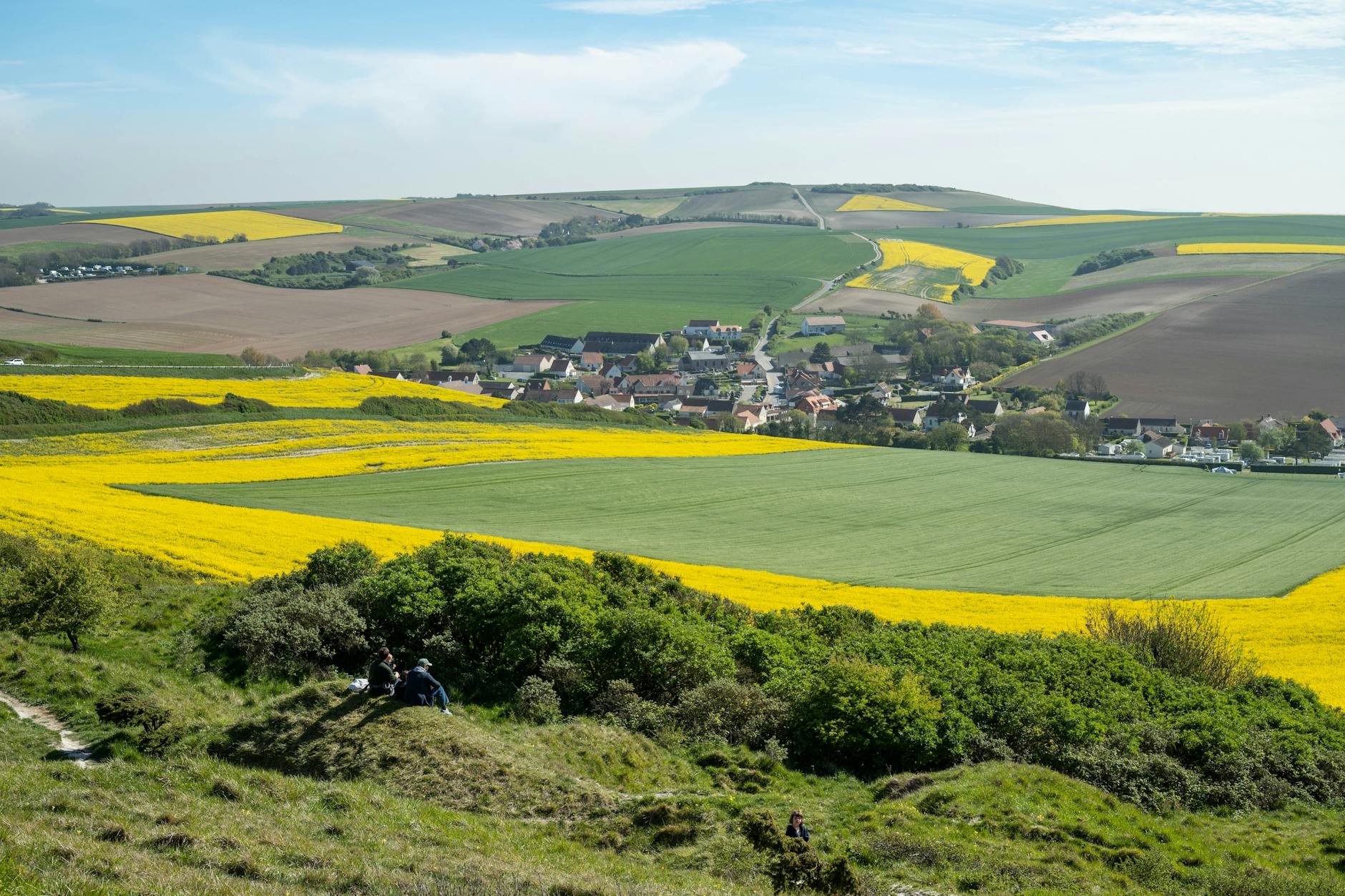 Lush green and yellow fields surround the quaint village of Escalles, France.